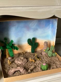 a desert scene made out of sand with cactus and rocks in the middle, sitting on top of a dresser