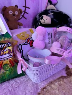 a teddy bear sitting next to a basket filled with toys and other items on a bed