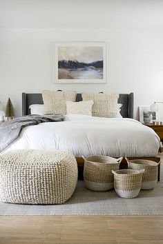 a bedroom with white bedding and baskets on the floor