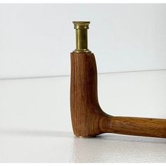 a wooden pipe with a brass fitting on the end and a white wall in the background