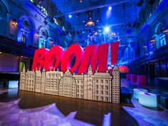 a large sign that says boom in front of a building with lights on the ceiling