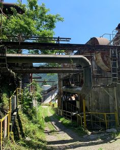 an old factory building with pipes running down it's sides and trees in the background