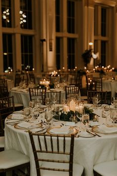 the tables are set with white linens and candles