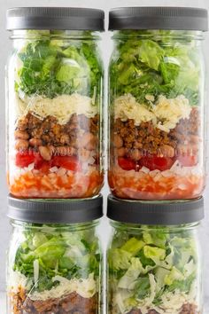 four mason jars filled with different types of vegetables and meats, all stacked on top of each other