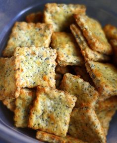 some crackers are in a blue bowl on a table or counter top, with black pepper sprinkled on them