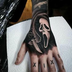 a person's hand with a black and white tattoo on it, holding a knife