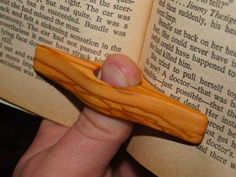 a person is holding an open book with a wooden object in it's hand