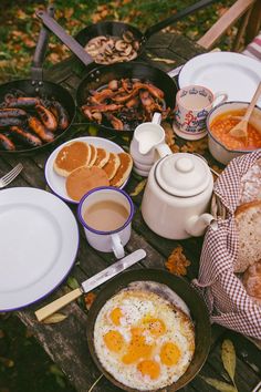 an outdoor picnic table filled with food and drinks, including eggs, sausages, bread