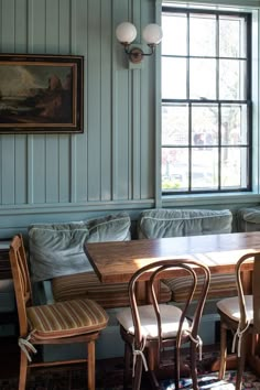 a dining room table with four chairs and a bench in front of the window,