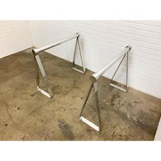 two metal frames sitting next to each other on the floor in front of a white brick wall