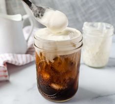 a spoon full of ice cream on top of a mason jar filled with iced coffee