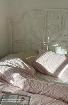 a white bed with pink sheets and pillows