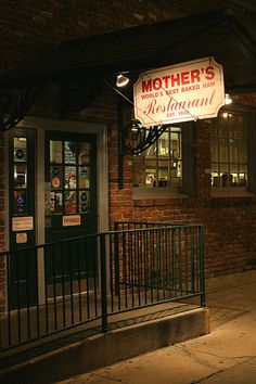 a restaurant sign hanging from the side of a building at night with lights on it