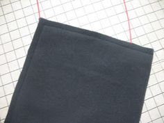 a piece of black cloth sitting on top of a cutting board next to scissors and thread