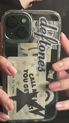 someone holding up their phone case with some stickers on it