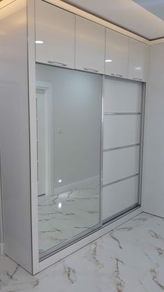 an empty room with white cabinets and marble flooring