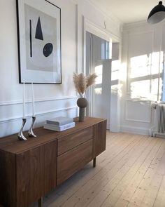 a living room with white walls and wood flooring on the sideboard is shown