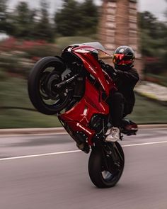 a man riding on the back of a red motorcycle