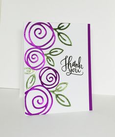 a handmade thank you card with purple flowers and green leaves on the front, white background