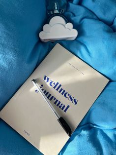 a book with a pen sitting on top of it next to a cloud shaped object