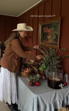 a woman in a cowboy hat is preparing food at a table with other items on it