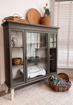 a gray cabinet with glass doors and baskets on top