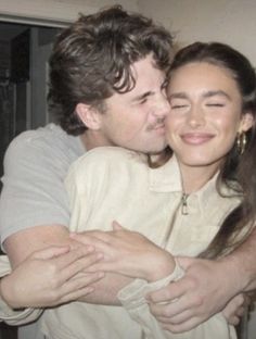 a man and woman hugging each other in front of a mirror with their eyes closed