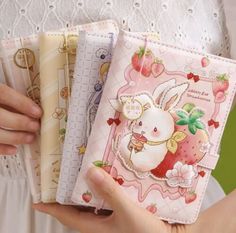 the woman is holding three small notebooks in her hands, one with an animal on it