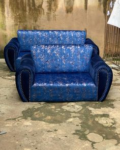 a blue couch sitting on top of a cement floor next to a wall with peeling paint