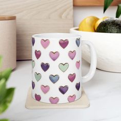 a coffee mug with hearts on it sitting next to some lemons and avocado