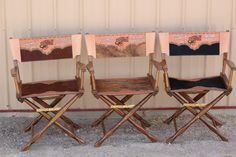 three wooden folding chairs sitting side by side in front of a metal wall with an advertisement on it