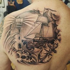 a man's back with a ship and lighthouse tattoo on it