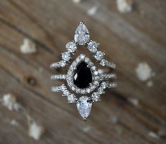 a diamond and black stone ring sitting on top of a wooden table