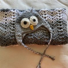 a crocheted owl hat laying on top of a bed