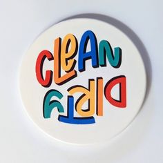 a white plate with the word clean dish painted on it's side, in multicolored letters