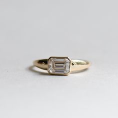 an engagement ring with a baguette cut diamond in the center on a white background