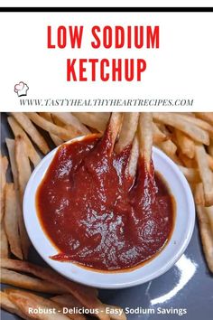 a bowl filled with ketchup next to french fries on top of a table