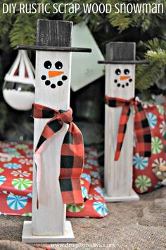 two snowmen made out of wooden sticks with red and black ribbon