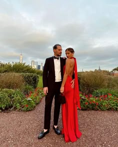 a man in a tuxedo and a woman in a red dress pose for the camera