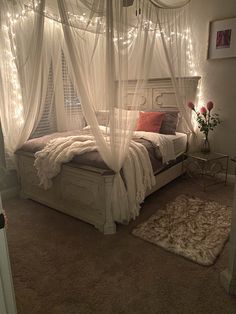 a bed with white curtains and lights on the ceiling in a room that has carpeted flooring