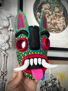 a person holding up a colorful mask with large teeth