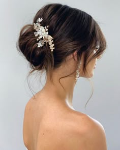 a woman wearing a wedding hair comb with flowers in it's back, looking off to the side