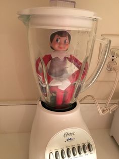 an elf doll in a blender sitting on top of a counter