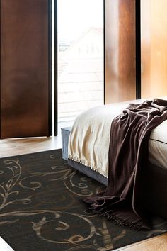 a bed with a blanket on top of it next to a sliding glass door in a bedroom