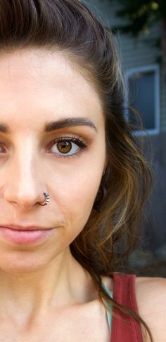 a close up of a person with a nose ring and piercing on her nose, looking at the camera