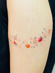 a woman's arm with flowers and fruit on the left side of her body