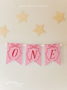 a pink banner with the word one hanging from it's side in front of stars