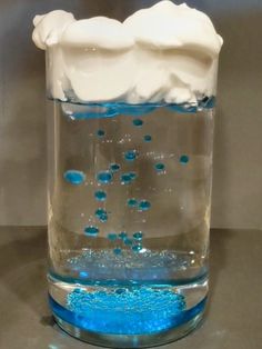 a glass filled with blue liquid and white foam on top of a metal countertop