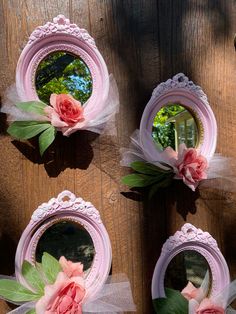 three pink mirrors with flowers on them sitting on a wooden table next to each other