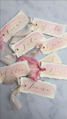 some pink and white tags with bows on them